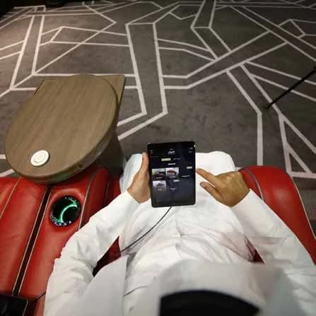 Guest reclining with a service tablet in a Flik Cinemas premium seat