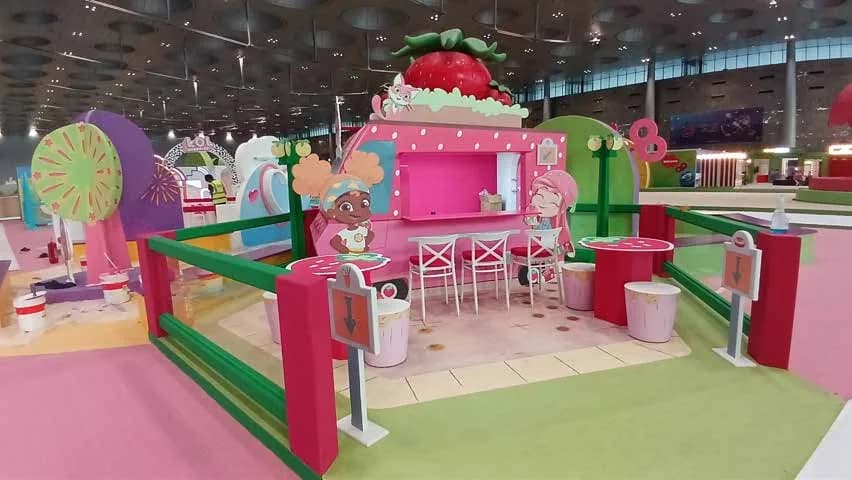 Strawberry-themed play activation with green turf and cutouts