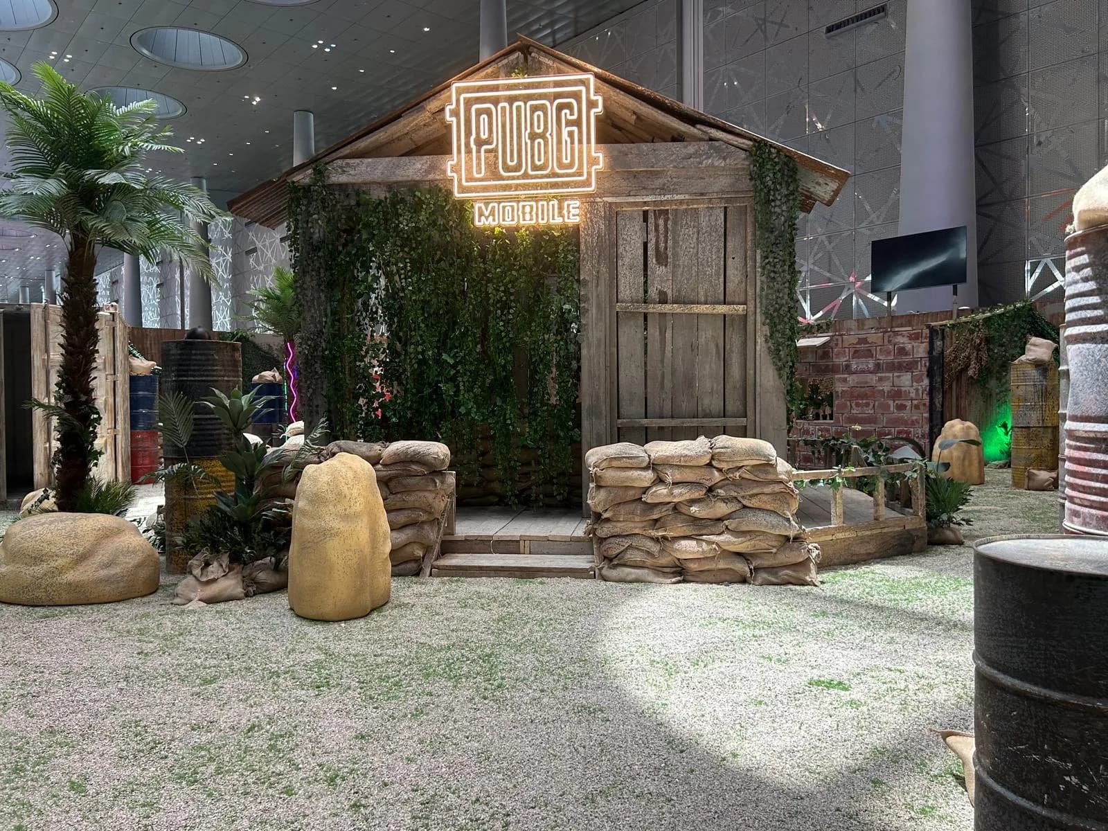 PUBG Mobile cabin entrance with neon sign and sandbag barricades