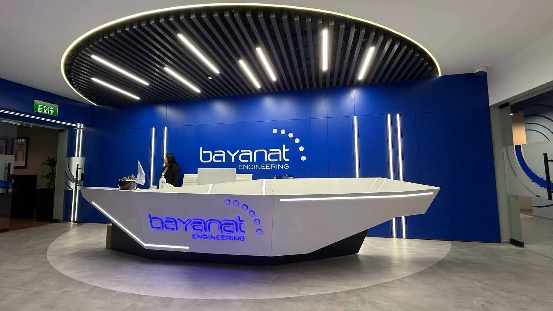 Bayanat Engineering reception desk beneath a circular lighting feature